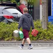 A man carrying containers at a Tesco Petrol Station in Bracknell, Berkshire. Picture date: Saturday September 25, 2021. PA Photo