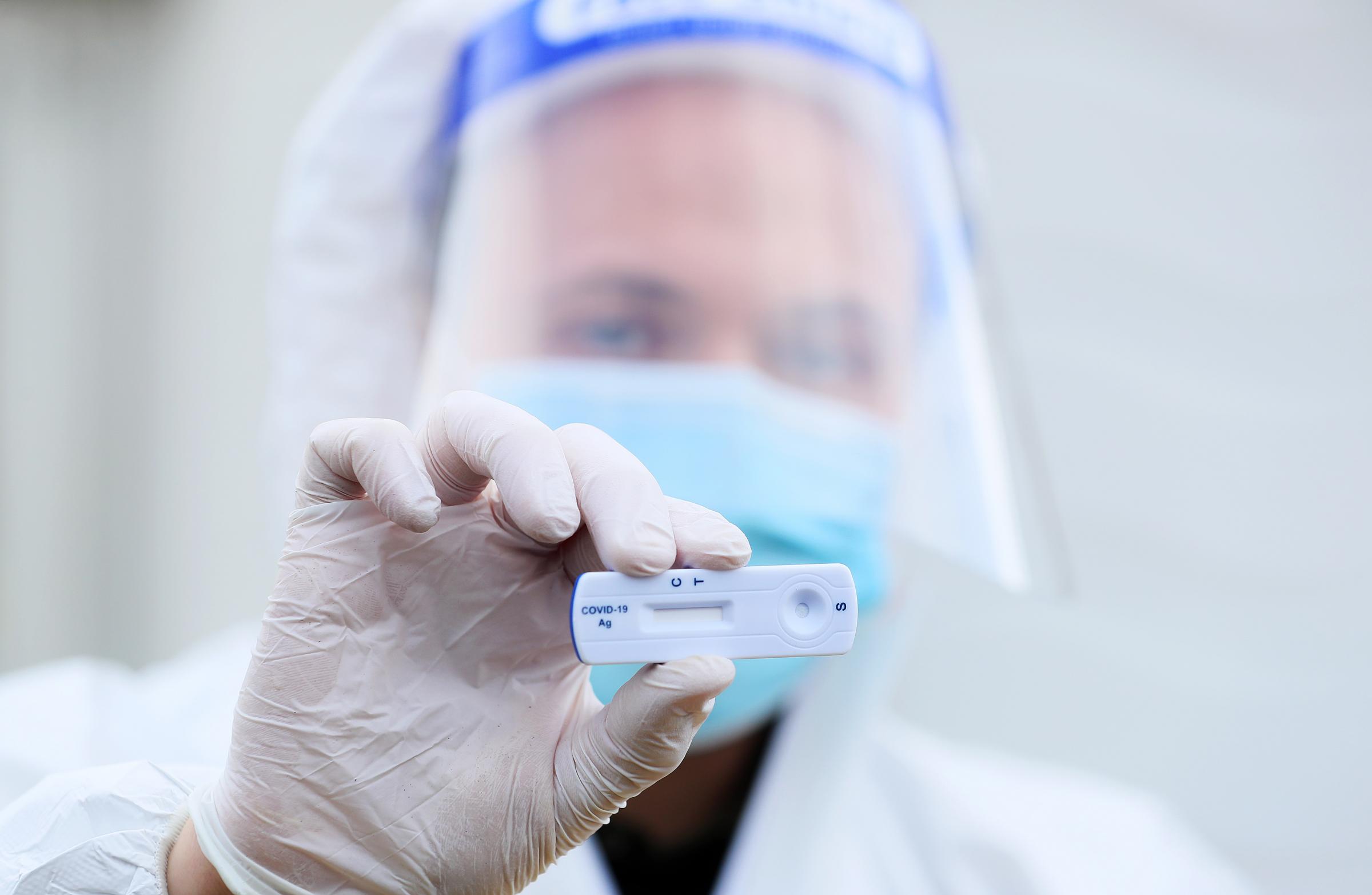 A lab technician holds a Healgen Covid-19 Rapid Antigen Test. stock image by PA